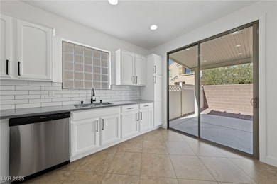 Kitchen featuring a sink, white cabinetry, backspl