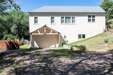 Rear view featuring stucco siding, metal roof, and an attached garage w/workshop and another closet room attached