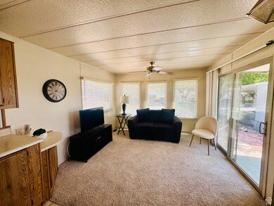 Living area with light carpet, ceiling fan, and a textured ceiling