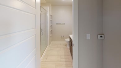 Bathroom featuring vanity, toilet, tile patterned floors, and a shower with shower door