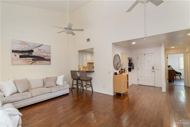 Living room featuring dark wood-style floors, visible vents, a ceiling fan, and baseboards