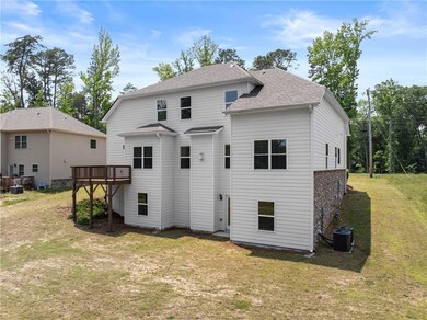Back of house with central AC, a yard, a wooden deck, and roof with shingles