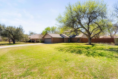 View of yard featuring driveway, a garage, and fe