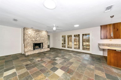 Unfurnished living room featuring stone tile floors, ceiling fan, and a fireplace