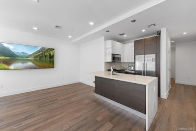 Kitchen with dark brown cabinetry, light stone countertops, hanging light fixtures, backsplash, and white cabinets
