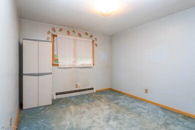 Spare room featuring carpet and a baseboard heating unit