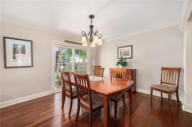 Dining area featuring a chandelier, crown molding, and dark wood finished floors