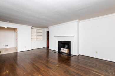 The well-proportioned living room is appointed with crown molding, built-in shelving and cabinetry, a gas fireplace with marble surround and gleaming hardwood floors.