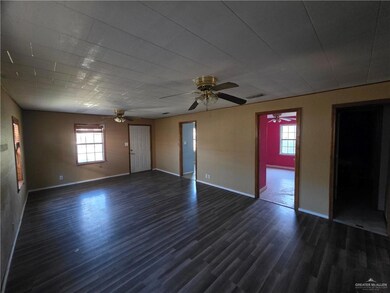 Empty room featuring dark wood-type flooring, plenty of natural light, and a ceiling fan