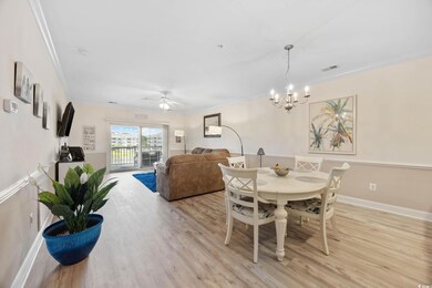 Dining area with crown molding, light wood-style floors, a chandelier, and a ceiling fan