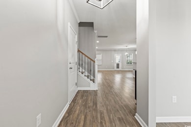 Foyer with wood finished floors, stairway, a chandelier, baseboards, and ornamental molding
