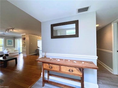Hallway featuring track lighting, wood finished floors, and baseboards
