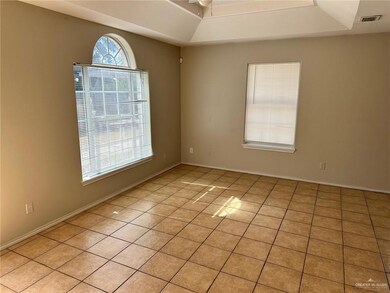 Empty room with light tile patterned floors, a ceiling fan, and a raised ceiling