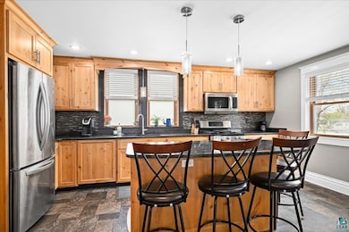 Kitchen featuring appliances with stainless steel finishes, a sink, dark countertops, backsplash, and recessed lighting