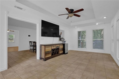 Living room featuring ceiling fan, light tile patterned floors, and plenty of natural light