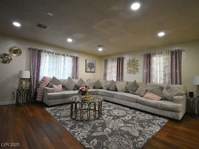 Living area with dark wood-style flooring and recessed lighting