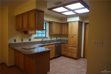 Kitchen featuring dark stone counters, sink, kitchen peninsula, light tile patterned floors, and stainless steel dishwasher
