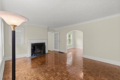 Unfurnished living room with baseboards, a textured ceiling, a tiled fireplace, arched walkways, and ornamental molding