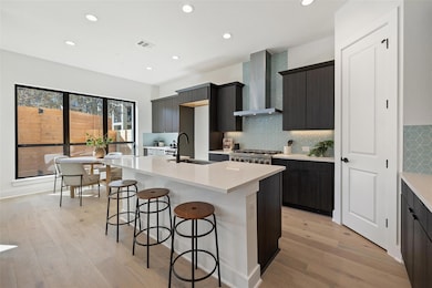 Kitchen featuring a sink, wall chimney exhaust ho