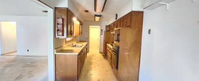 Kitchen featuring light countertops, brown cabinetry, oven, and concrete flooring