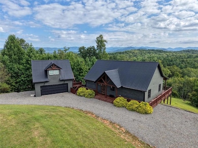 View of front facade featuring a front yard, a metal roof, a deck with mountain view, gravel driveway, and a view of trees