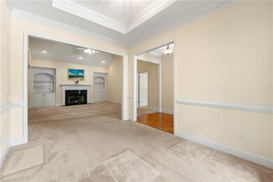 Unfurnished living room featuring carpet flooring, crown molding, a fireplace with flush hearth, and baseboards