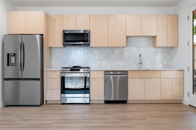Kitchen with stainless steel appliances, light br