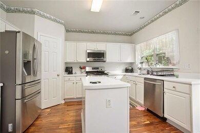 Kitchen featuring stainless steel appliances (Refrigerator not included) white cabinets, dark wood finished floors, a center island, and a sink