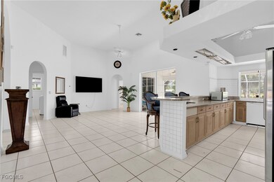 Kitchen featuring open floor plan, a towering ceiling, a breakfast bar area, arched walkways, and white appliances