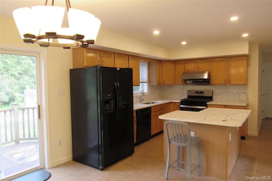 Kitchen with black appliances, decorative light fixtures, recessed lighting, quartz counters and backsplash, and a chandelier