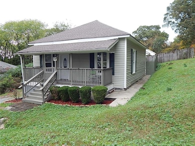 Bungalow with roof with shingles, covered porch, and a front lawn