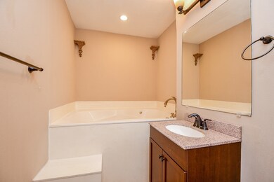 This bathroom features a cozy corner tub with eleg