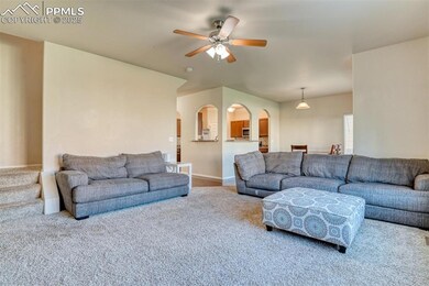 Living area featuring carpet flooring, arched walkways, and ceiling fan