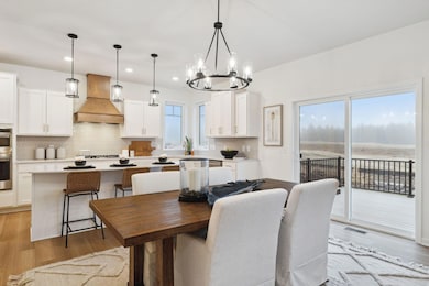 Bright dining area with large windows, elegant lighting, and seamless flow to the kitchen - perfect for everyday meals or entertaining guests.   (Picture of Model home, colors and material may vary.)