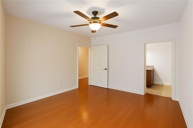 Unfurnished bedroom with dark wood finished floors, ceiling fan, and ensuite bath