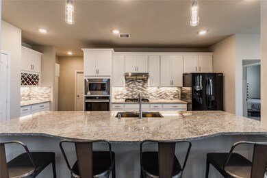 This kitchen is by far any chef’s dream! This spacious kitchen features white stained wood cabinets, granite countertops, SS appliances, custom tile backsplash, recessed lighting with additional custom pendant lighting, extended counter space, granite kitchen island with double sink and space for breakfast bar, and a walk-in pantry all overlooking your huge family room.