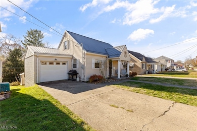 View of front of home featuring a front lawn, a metal roof, driveway, and an attached garage