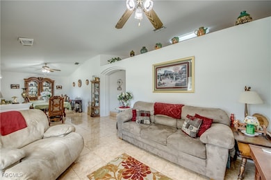 Living area with ceiling fan, arched walkways, and tile patterned floors