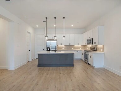 Designer kitchen featuring a statement island, quartz countertops, stainless steel appliances, and elegant pendant lighting