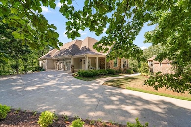 View of front of home with covered porch, a standing seam roof, driveway, metal roof, and stone siding