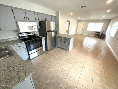 Kitchen featuring gray cabinetry, appliances with stainless steel finishes, light tile patterned floors, a peninsula, and open floor plan