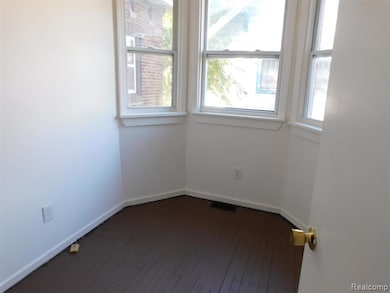 Spare room featuring dark wood-style floors and baseboards