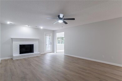 Unfurnished living room with ceiling fan, wood finished floors, a fireplace, and a textured ceiling