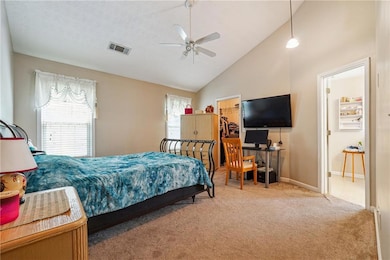 Carpeted bedroom with a spacious closet, high vaulted ceiling, and a ceiling fan