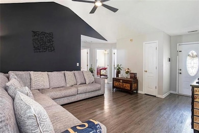 Living room with a ceiling fan, wood finished floors, vaulted ceiling, and baseboards