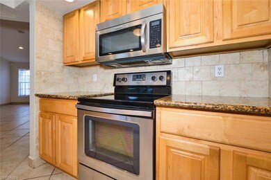Kitchen featuring stainless steel appliances, light tile patterned flooring, stone counters, tasteful backsplash, and baseboards