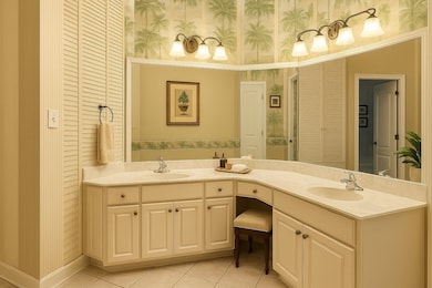 Full bathroom featuring wallpapered walls, double vanity, tile patterned flooring, and a closet