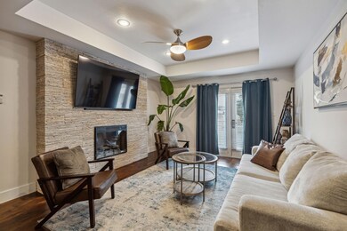 Living room with a tray ceiling, ceiling fan, and 