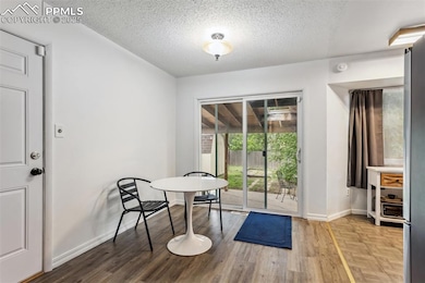 Unfurnished dining area featuring baseboards, a textured ceiling, and wood finished floors