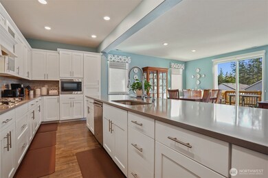 Gourmet kitchen with gas cooktop, double wall oven, french door refrigerator, stainless appliances, slab quartz countertops, center island eating bar that opens to the great room (living and dining rooms).